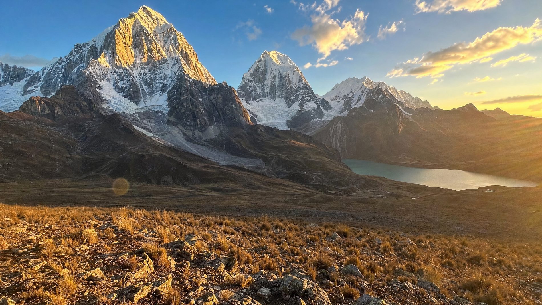 Evening light on the glaciated peaks of the Cordillera Huayhuash above the high puna, a glacial lake in the valley below.